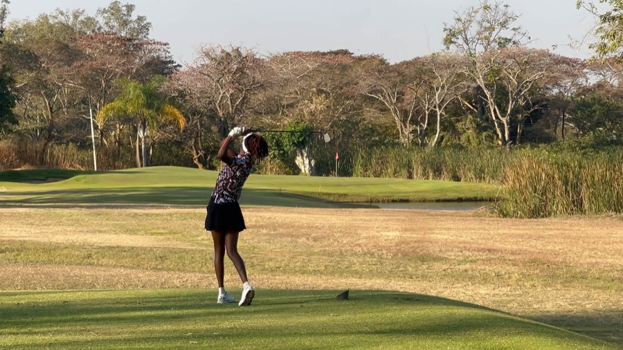 A golfer plays across the water towards a green