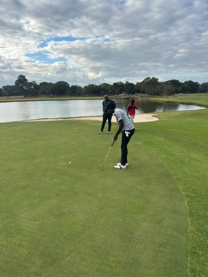 A golfer plays towards a green beside the water